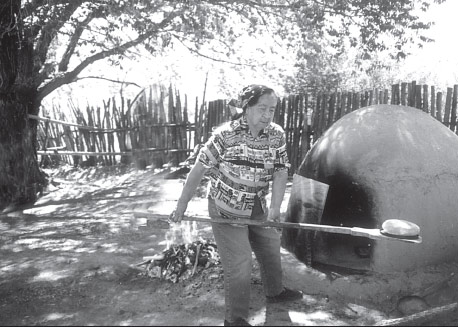 Image: Woman putting bread in horno native american